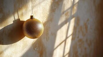 A single golden ornament hanging against a neutral backdrop near the holiday season photo