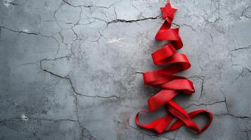 Creative arrangement of red ribbons and decorations resembling a Christmas tree on textured surface photo