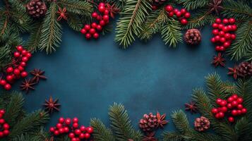 Festive arrangement of pine branches, red berries, and pine cones on a blue surface in winter photo