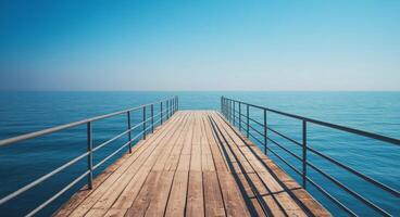 Wooden pier extending over calm blue waters on a clear sunny day photo