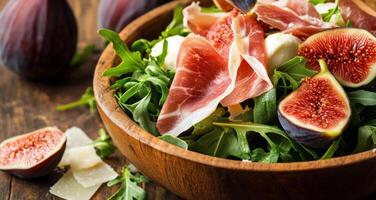 Delicious fig and prosciutto salad with arugula and cheese on a rustic wooden table photo