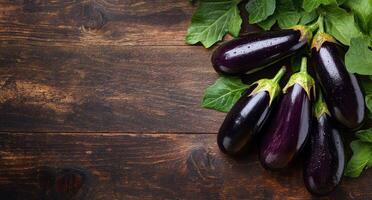 Freshly harvested eggplants and spinach on a rustic wooden table in natural lighting photo