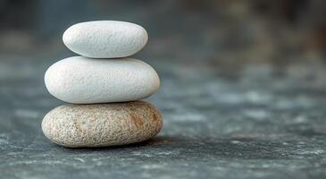 A balanced stack of smooth stones resting on a textured surface in natural light photo