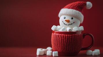 A cheerful snowman nestled in a red mug surrounded by marshmallows during winter festivities photo