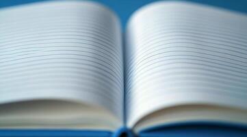 A blank notebook lies open on a blue surface, inviting creativity and ideas to flow freely photo