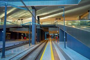 Modern train station platform with escalators and empty railway tracks. Architecture of transportation infrastructure and urban design photo