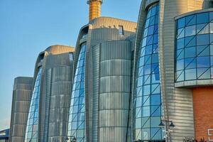 Industrial building with futuristic design. Factory exterior with curved metallic facades and large glass windows. Modern architecture and innovation concept photo