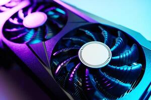Close-up of high-performance graphics card with cooling fans illuminated by neon lighting. Modern card for gaming and advanced computing photo