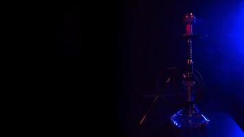 hookah with a glass flask with hot coals in a bowl on the table with blue smoke video