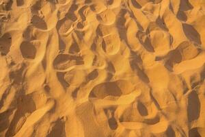 Close up of sand pattern of a beach in the summer. Sand texture background. Brown desert pattern from tropical beach. photo