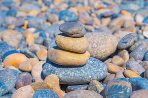 Symbolic scales of stones against the background of the sea and blue sky. Concept of harmony and balance. Pros and cons concept. Pyramid stones balance on the sand of the beach with blurred background photo