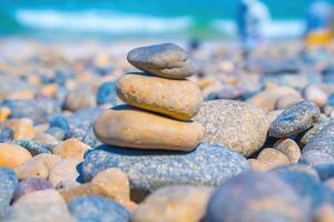 Symbolic scales of stones against the background of the sea and blue sky. Concept of harmony and balance. Pros and cons concept. Pyramid stones balance on the sand of the beach with blurred background photo