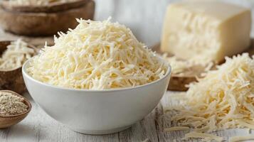 Deliciously shredded cheese fills a bowl, accompanied by a block and scattered shreds photo