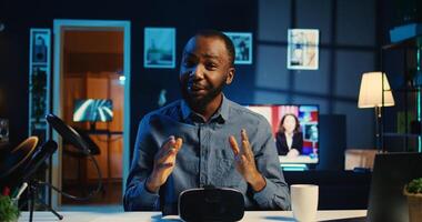 Tech content creator filming unboxing of newly released gaming VR glasses for audience in neon illuminated home studio. BIPOC internet star offers virtual reality headset recommendation to subscribers photo
