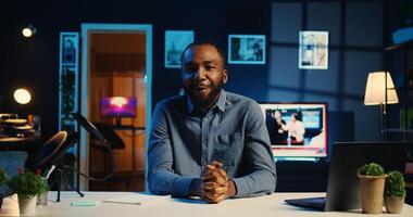 Influencer in home studio using professional camera and microphone to film live broadcast for online streaming platforms, talking with fans. African american online star hosts q a session with viewers photo