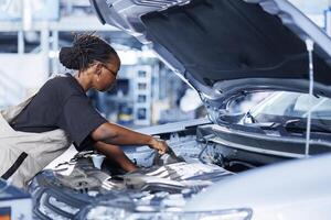 Auto repair shop mechanic expertly examines car engine using advanced mechanical tools, ensuring seamless automotive performance. Efficient professional in garage conducts routine vehicle checkup photo