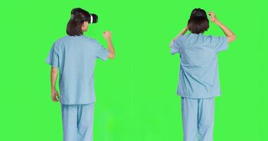Medical personnel uses virtual reality eyewear against greenscreen set while using new interactive 3D headpiece. Clinical healthcare specialist using artificial intelligence vision. photo
