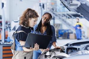 Mechanic in car service ordering new engine for damaged vehicle using laptop. Employee next to client looking online for components to replace old ones in malfunctioning automobile photo