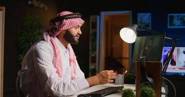 Muslim worker in call session with therapist, asking for advice, feeling down. Remotely working Middle Eastern employee in internet consultation with psychologist from stylish cozy home photo