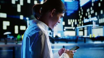 Aimless man strolling around city streets at night, chatting with his friends using smartphone in urban setting. Relaxed person enjoying empty town with no vehicles, using mobile phone photo