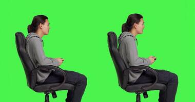 Player having fun with rpg competition over greenscreen in studio, playing videogames online with friends. Talented joyful guy enjoying gaming, game enthusiast sitting on chair. photo