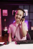 Gen Z content creator filming for online channel in dimly lit home studio, presenting gaming headphones to subscribers. Media star kid testing audio listening device for viewers photo