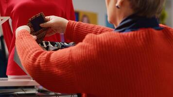 Elderly woman browsing through clothes in Christmas decorated shopping store, trying to pick perfect necktie for husband as xmas present during winter holiday season, close up photo
