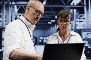 Senior employees preventing strain on data center devices caused by AI applications driving up power usage. Competent workers maintenancing server cabinets doing intense computations photo