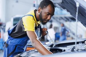 Mechanic in car service using professional mechanical tool to repair broken brakes. Competent worker in garage fixing client automobile, ensuring optimal automotive performance photo