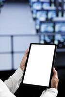 Close up shot of mock up tablet used by experienced serviceman in data center using server cabinets to deliver massive computing power, control network resources, process and store datasets photo