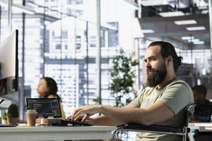 Person with paraplegia creating machine learning models that can process and analyze data to automate decision making processes. IT expert with disability programming in office, sitting in wheelchair photo