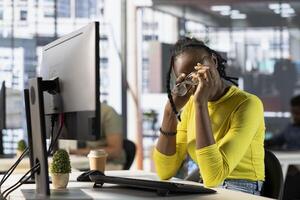 Tired programmer having strained eyesight from overworking, doing software quality assurance. Woman at work removing eyeglasses to rub eyes, looking at PC screen for too long while inspecting coding photo