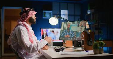 Arab man in online teleconference meeting with remotely working colleagues, chatting about task progress. Muslim employee working from home discussing with project colleagues during videocall photo