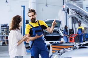 Skilled serviceman in repair shop using holographic augmented reality to show customer car performance parameters. Garage employee using futuristic vr headset to inform client what needs to be fixed photo