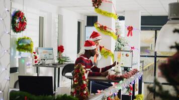 Zoom out shot of coworkers brainstorming ideas for project during Christmas season in festive ornate office. Workers in multicultural workplace adorn with xmas tree and wreaths photo