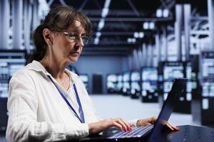 Elderly adept technician inside high tech facility providing computing resources needed for AI to process extensive datasets for training. Server hub storing data used for machine learning photo