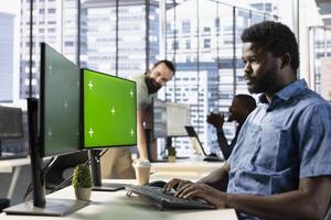 Focused employee analyzing datasets on green screen computer, comparing marketing graphs and checking accounting figures. African american worker solving tasks for team project on mockup PC photo