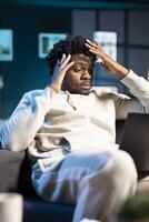 African american employee struggling to concentrate while working from home, hurting from severe headache. Tired teleworker exhausted after sleepless night, struggling to remain focused on work photo