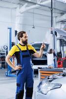 Repairman in repair shop using augmented reality holograms to check car blueprint during checkup. Hardworking garage employee using futuristic AR technology to examine malfunctioning vehicle photo