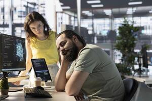Programmer caught asleep at desk by manager while developing AI machine learning APIs solving complex problems. Tired sleeping man woken up by team leader while training predictive models photo