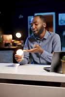 Content creator talking about house improvement topic, showing newly launched smart light bulb to subscribers. Tech guru presenting WIFI home automation device to fans photo