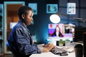 African American female freelancer working on laptop, managing data, programming, and ensuring cyber security. Young black woman using a digital device displaying code and a network system. photo