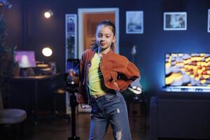 Zealous kid showcasing enchanting dance routine on social media networks, participating in viral challenge. Excited gen Z dancer filming in apartment studio for internet audience photo