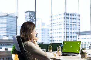 Woman company leader looking at isolated chroma key display in high end urban office, ambitious driven CEO with executive power. Businesswoman with strategic thinking in corporation. photo