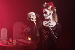 Woman doing Hamlet scene at Day of the Dead event to remember the deceased. Lady posing with skull in hand at theatre play for Mexican holiday of remembrance for those who have passed photo
