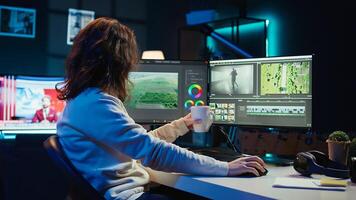 Videographer using editing software to assemble footage into cohesive final result while enjoying cup of coffee. Specialist color correcting clips while drinking hot beverage, camera B photo
