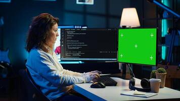 Developer doing software debugging on green screen PC at home, checking lines of code displayed on monitors. IT professional in living room fixing coding problems on mockup computer, camera A photo