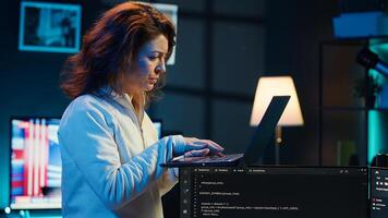 Developer doing software debugging using laptop, checking glitches in lines of code, upset about errors. Woman walking around home fixing coding issues using notebook device, camera A photo