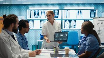 Diverse medical team examining test results and discussing innovative treatment plans at a modern clinic to enhance patient care quality. Doctors and nurses review x ray scans. Camera B. photo