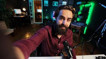 Content creator using professional recording equipment to film vlog channel intro, talking with subscribers. POV shot of man recording himself greeting fans, covering different subjects photo